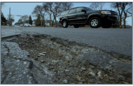 Traffic passes a pothole Thursday on Milwaukee’s east side. 1000 Friends of Wisconsin and the Coalition for More Responsible Transportation is calling for money that is being used for an I94 expansion to instead be used for local roads. (Staff photo by Kevin Harnack)