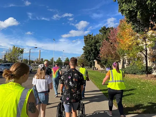 a group from the class embarks for the audit pushing a wheelchair and wearing reflective vests