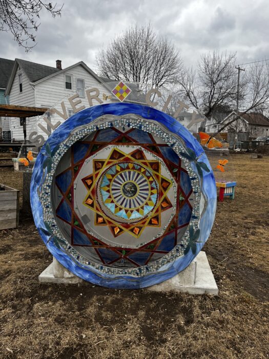 Image shows a public art piece of a 3d mandala sculpture with the word Silver City  on top.