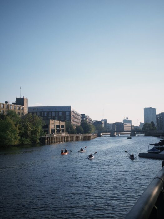 Image shows a southward bound view of the Milwaukee River with kayakers rowing down the river.