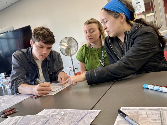 Three participants discussing and annotating maps as part of Madison Community Transportation Academy