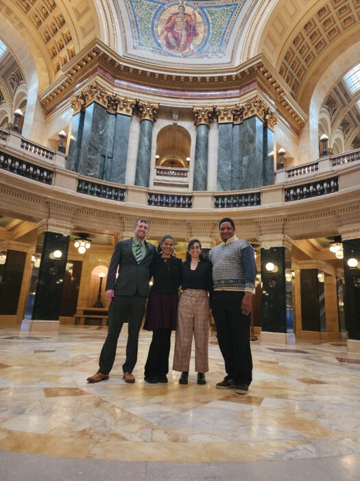 Ken Smith, Solana Patterson-Ramos, Tehila Cohen, and Jarrett English pose inside the dome of the Wisconsin State Capitol